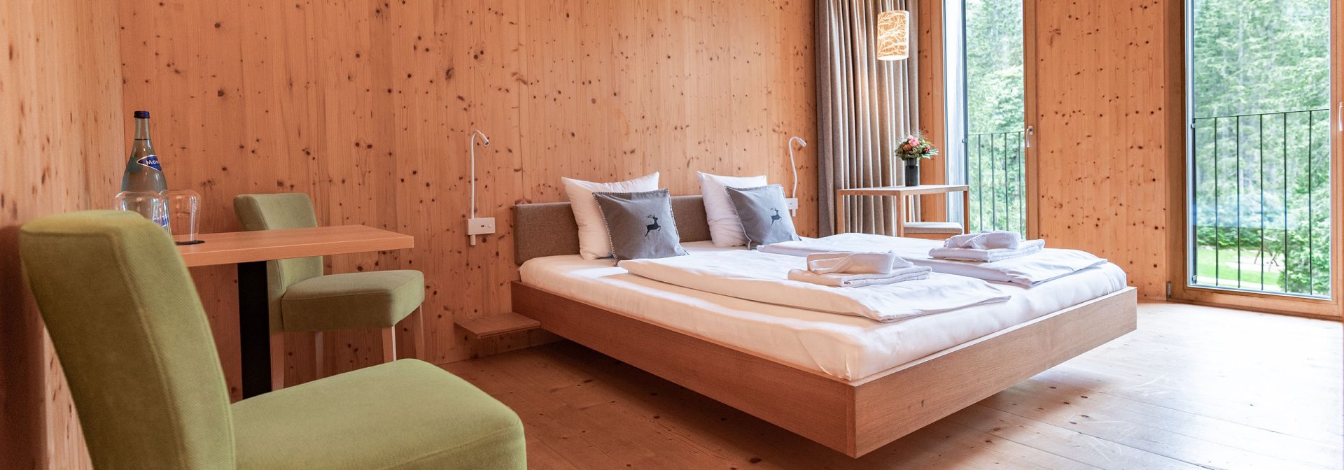 Holzverkleidetes Hotelzimmer mit Stühlen und einem Bett