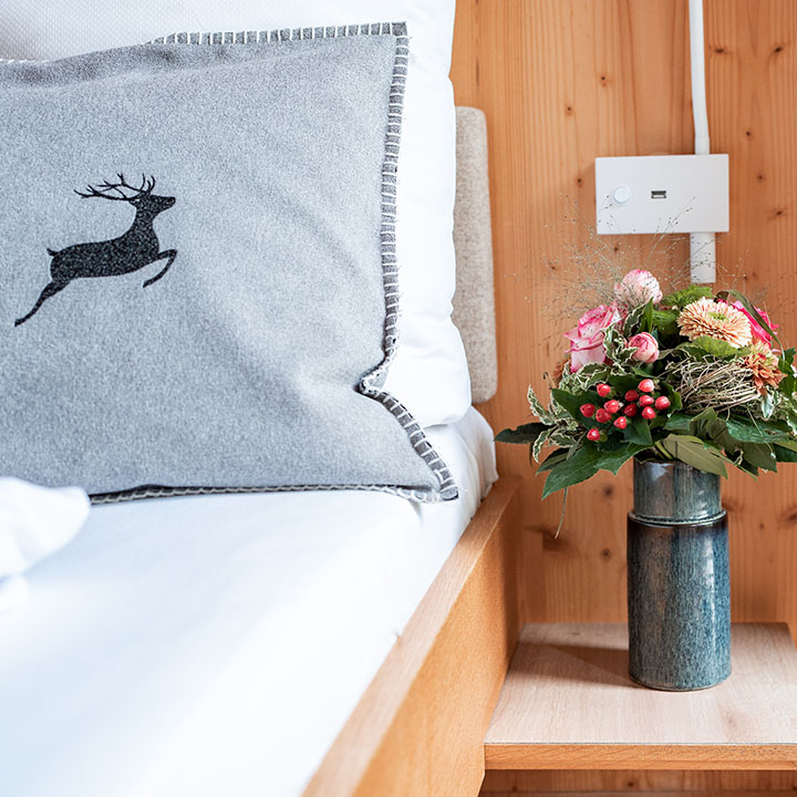 Ein rosaner Blumenstrauß in einer Vase auf dem Tisch neben einem Bett