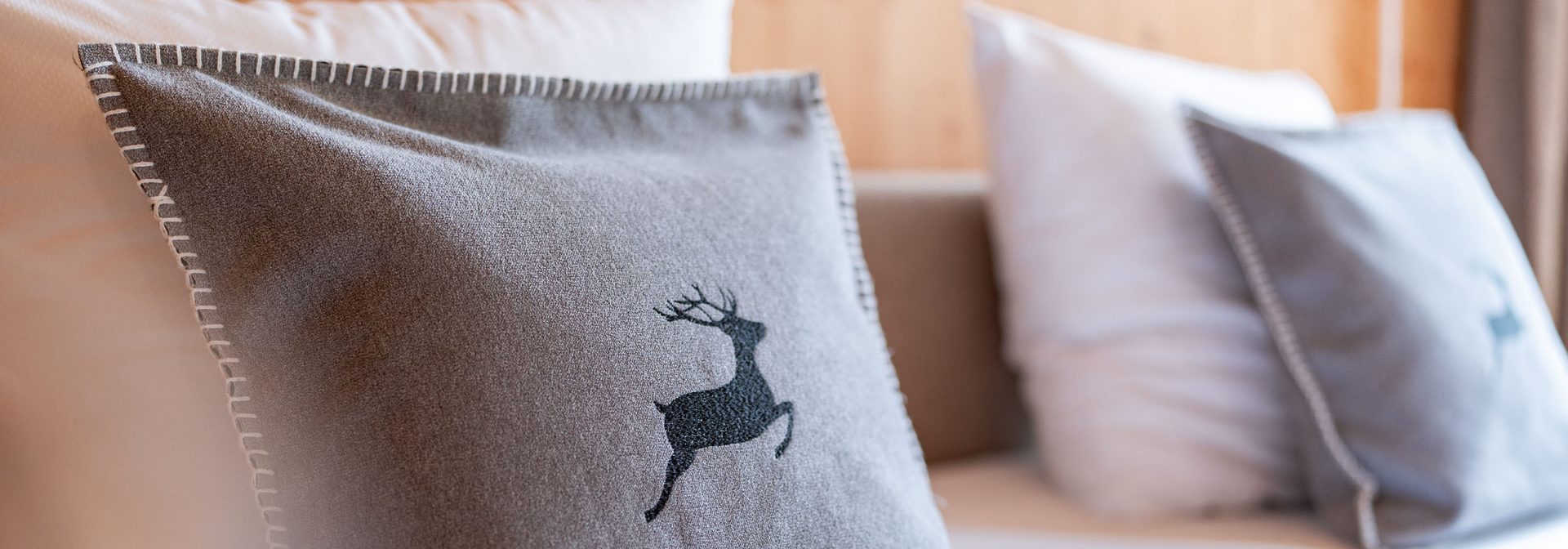 Zwei graue Kissen mit Hirschmotiv auf einem Bett
