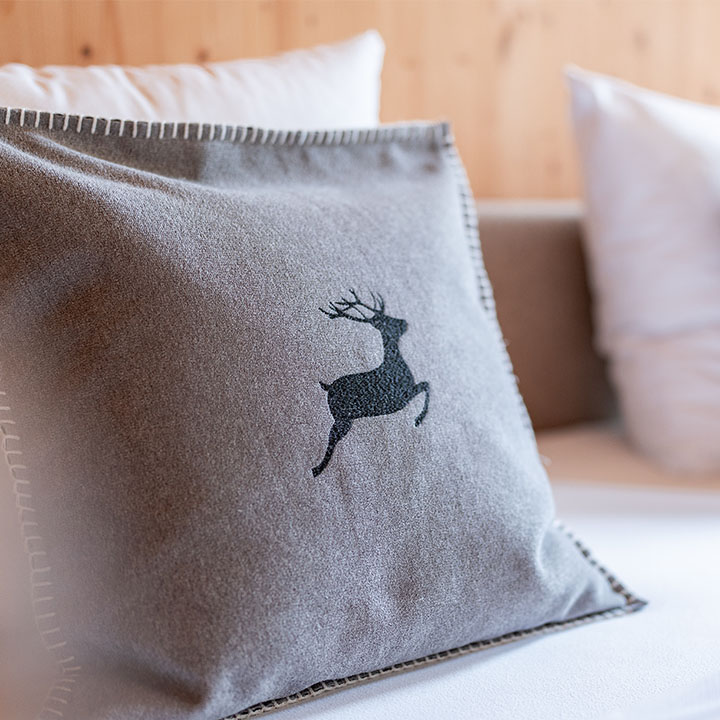 Graues Kissen mit Hirschmotiv auf einem Bett
