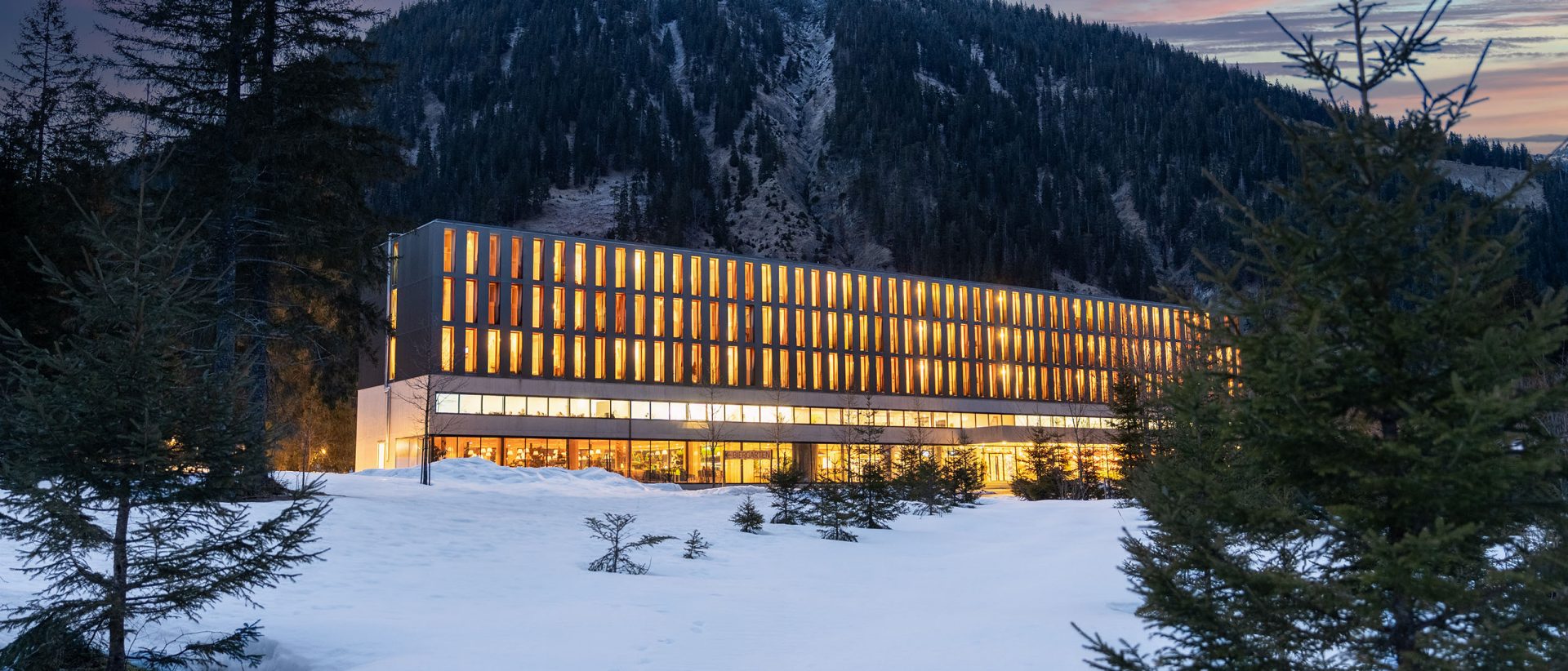 Ein Hotel vor einer Bergkulisse, umgeben von Schnee.