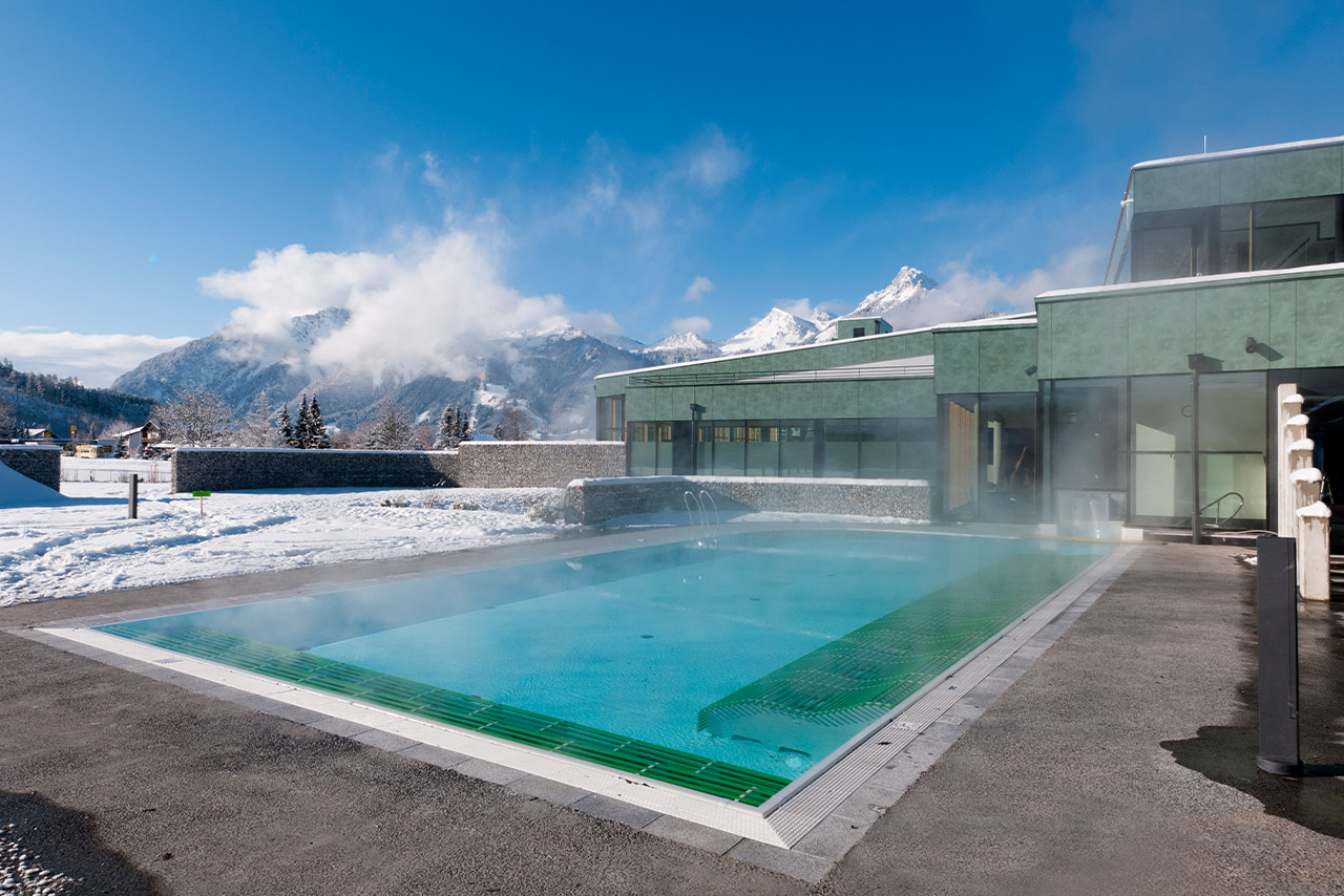Der Außenbereich der Alpentherme Ehrenberg Reutte. Ein dampfender Swimmingpool. 