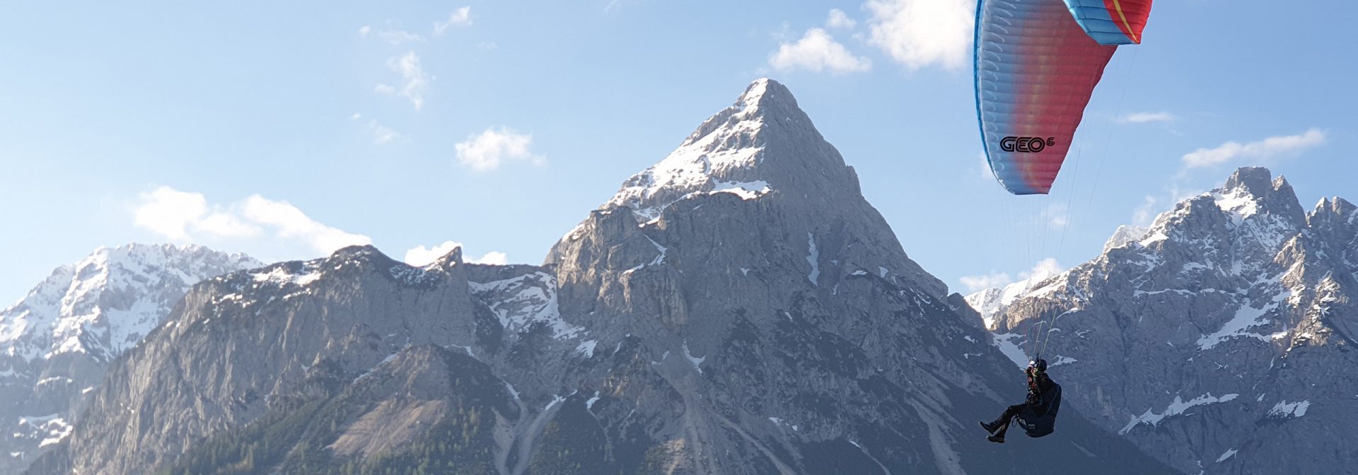 Eine Person beim Paragliding vor einer Bergkulisse