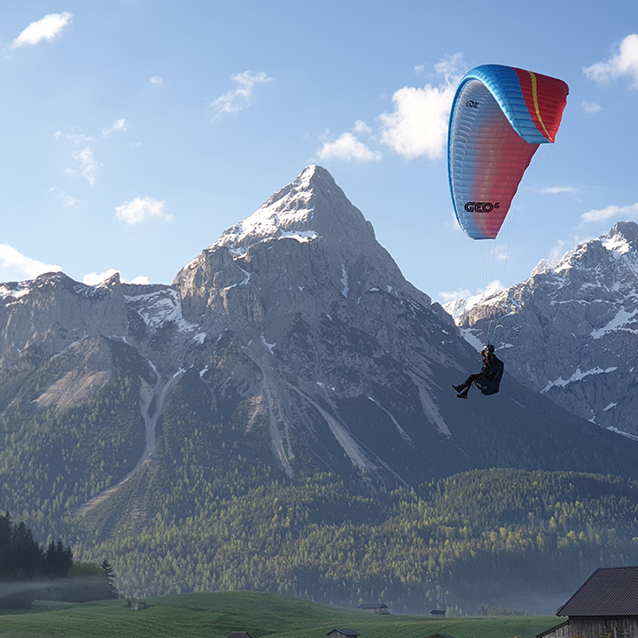 Eine Person beim Paragliding vor einer Bergkulisse