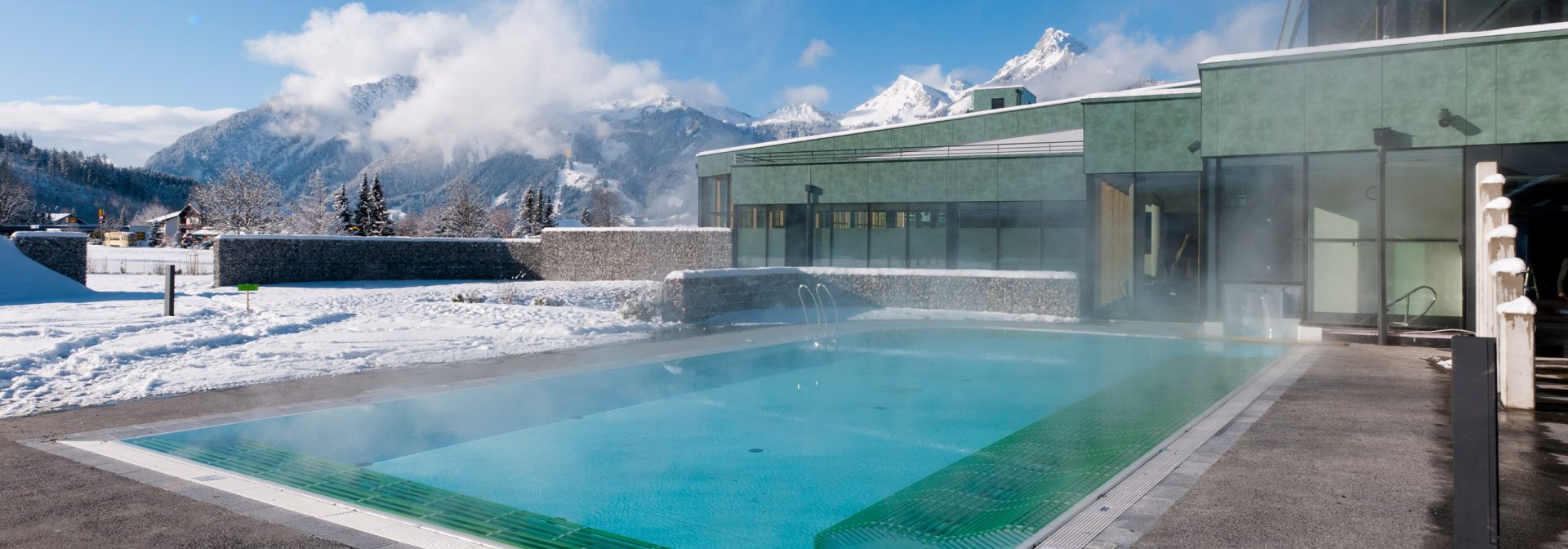 Der Außenbereich der Alpentherme Ehrenberg Reutte. Ein dampfender Swimmingpool. 