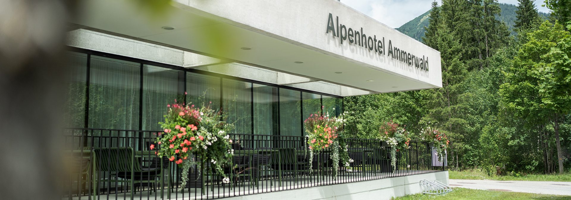 Außenansicht des Alpenhotel Ammerwald, dekoriert mit Blumen.