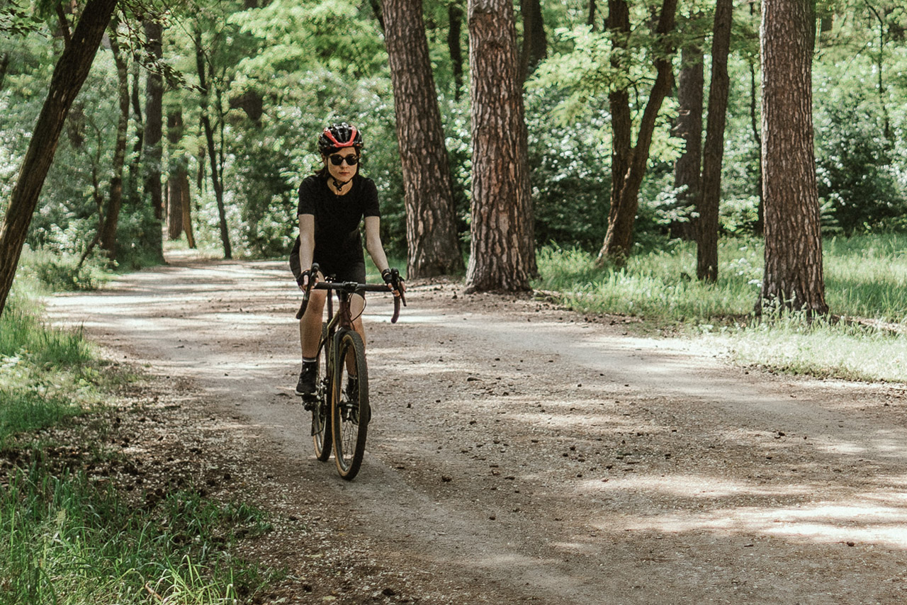 Eine Frau, die im Wald Gravelbike fährt.