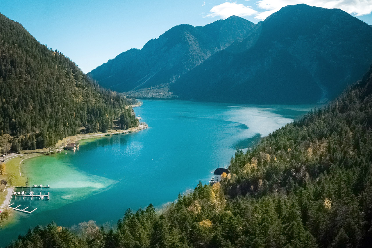 Der Plansee, ein türkis leuchtender See, der von Bergen und Bäumen umgeben ist. 