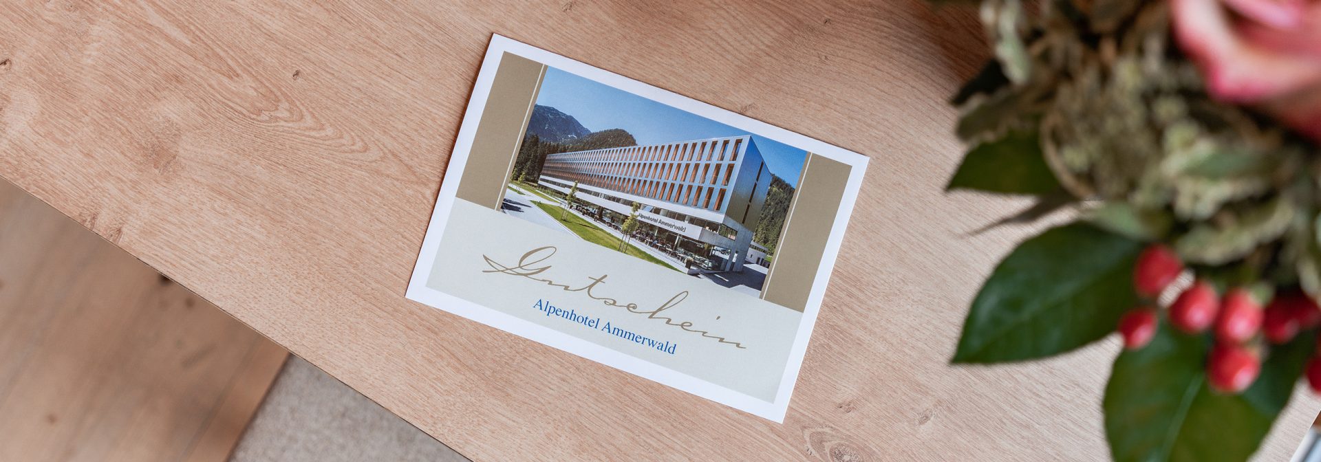 Bild eines Beispiel Gutscheines für das Alpenhotel Ammerwald, auf dem ein Bild vom Hotel abgebildet ist. 