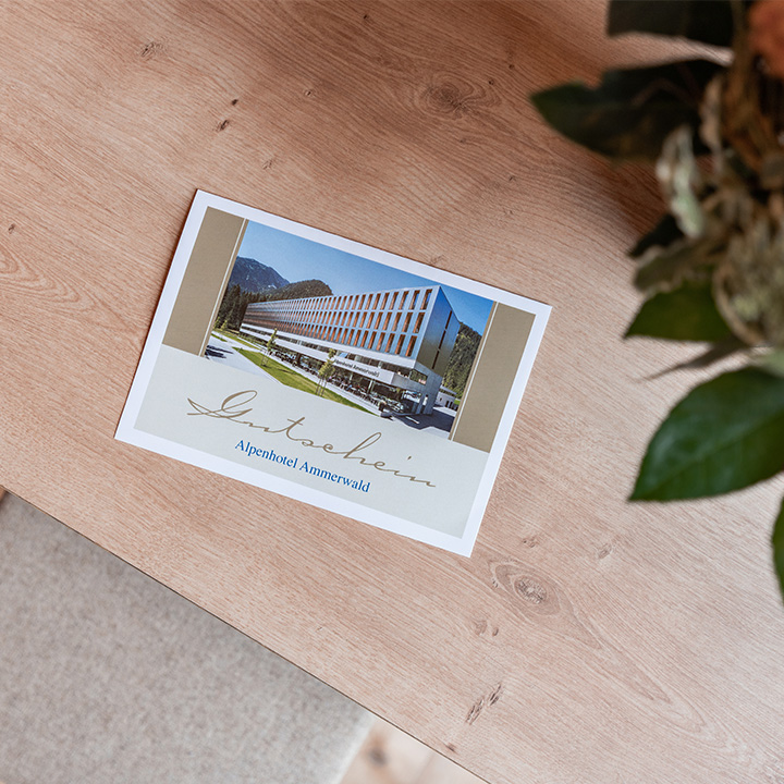 Bild eines Beispiel Gutscheines für das Alpenhotel Ammerwald, auf dem ein Bild vom Hotel abgebildet ist. 