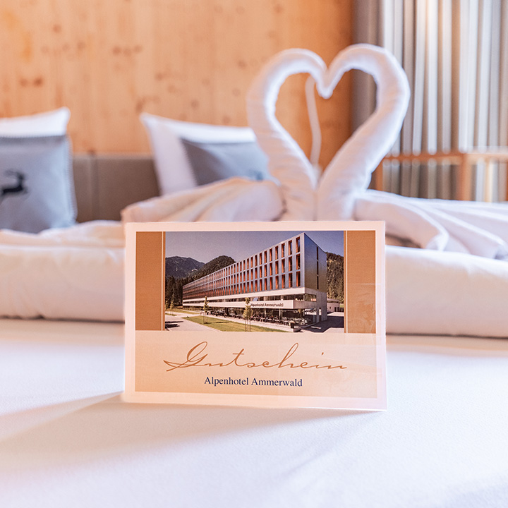 Bild eines Beispiel Gutscheines für das Alpenhotel Ammerwald, auf dem ein Bild vom Hotel abgebildet ist.