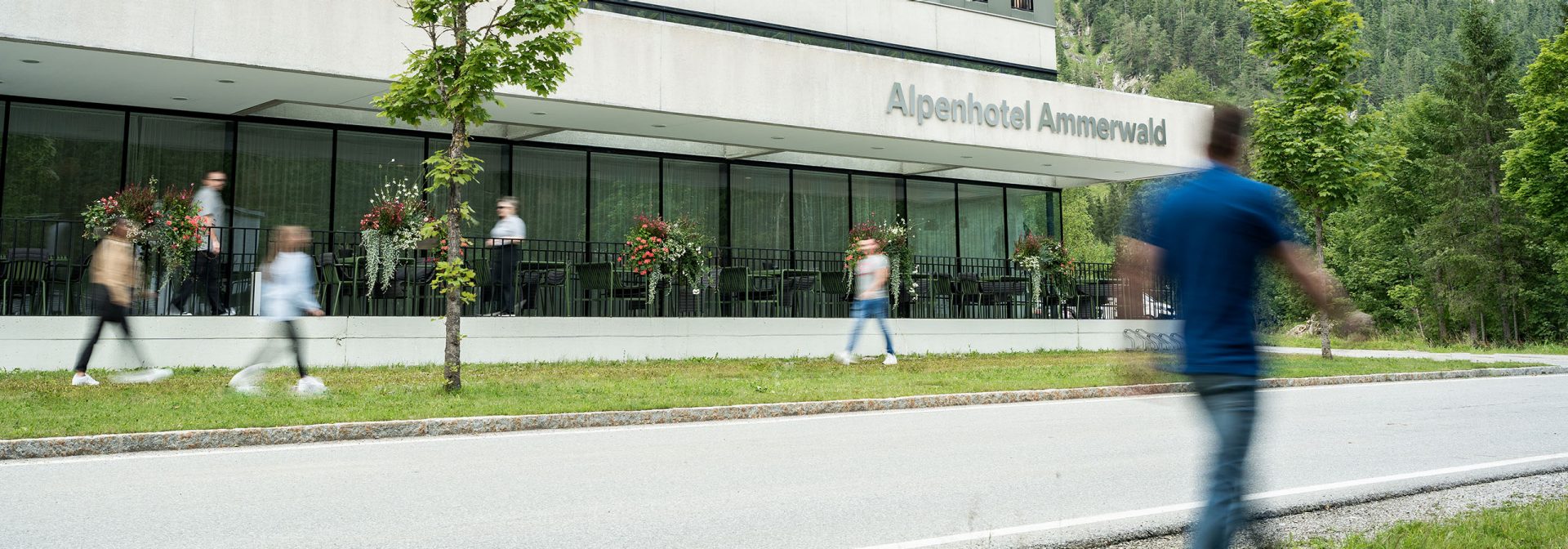 Modernes Gebäude des Alpenhotels Ammerwald mit Gästen im Freien