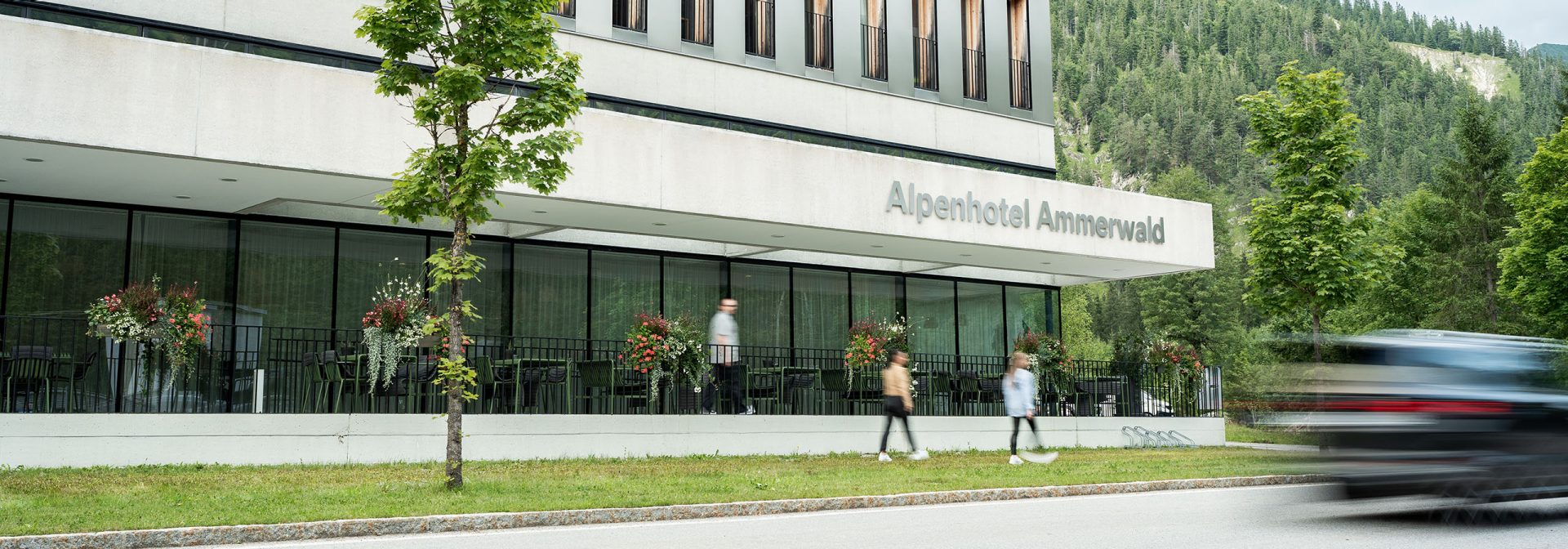Modernes Gebäude des Alpenhotels Ammerwald mit Gästen im Freien