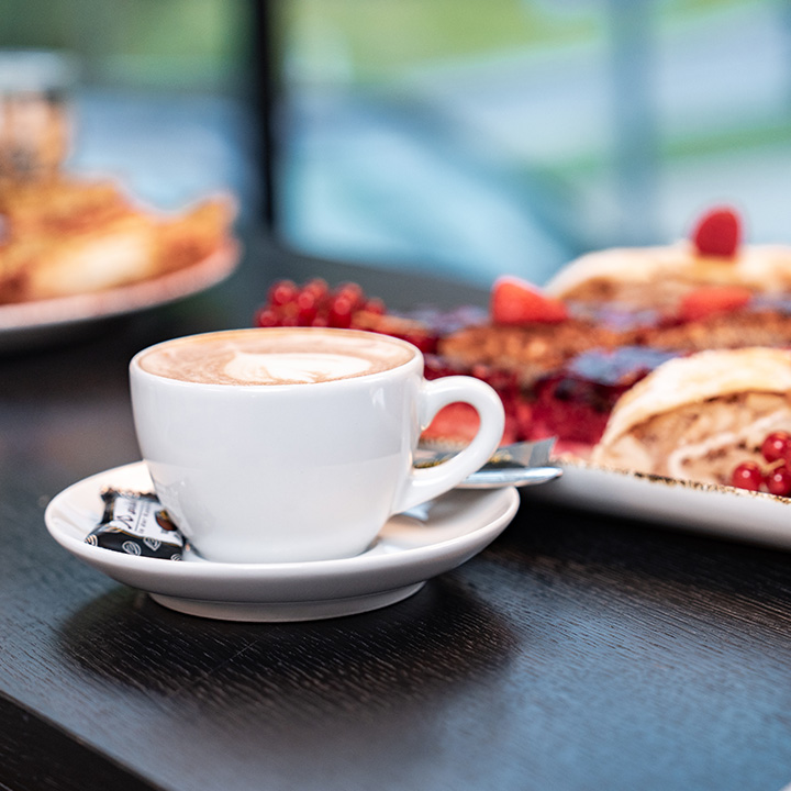 Eine Tasse Cappuccino steht neben etwas süßem.