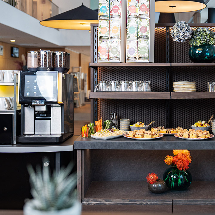 Tische, aneinandergereiht, mit Papier, Stift, Wasserflasche und Glas darauf.