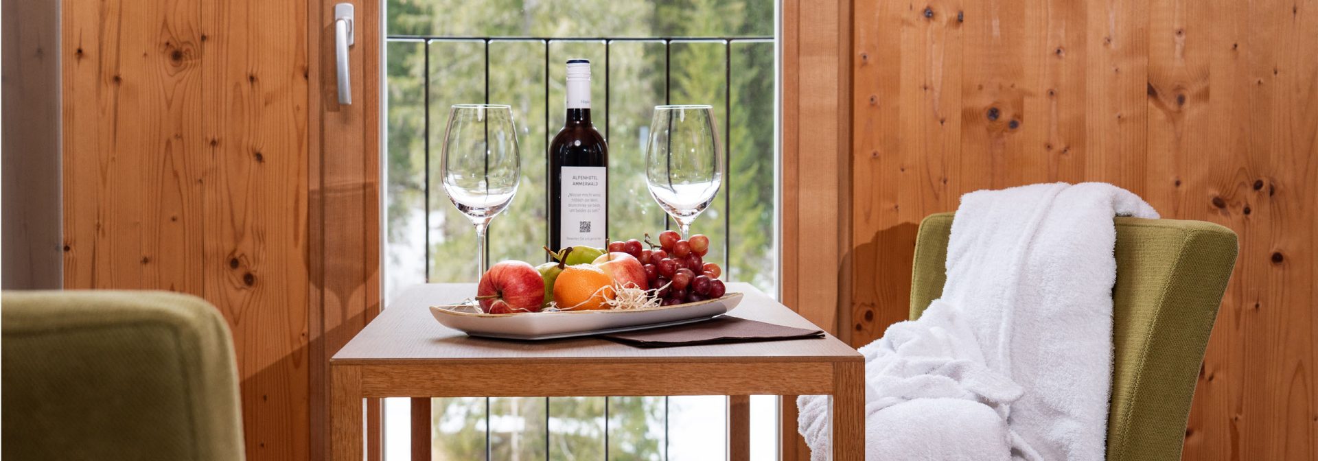 Ein Tisch, der mit einer Auswahl an Früchten und einer Flasche Wein dekoriert ist.