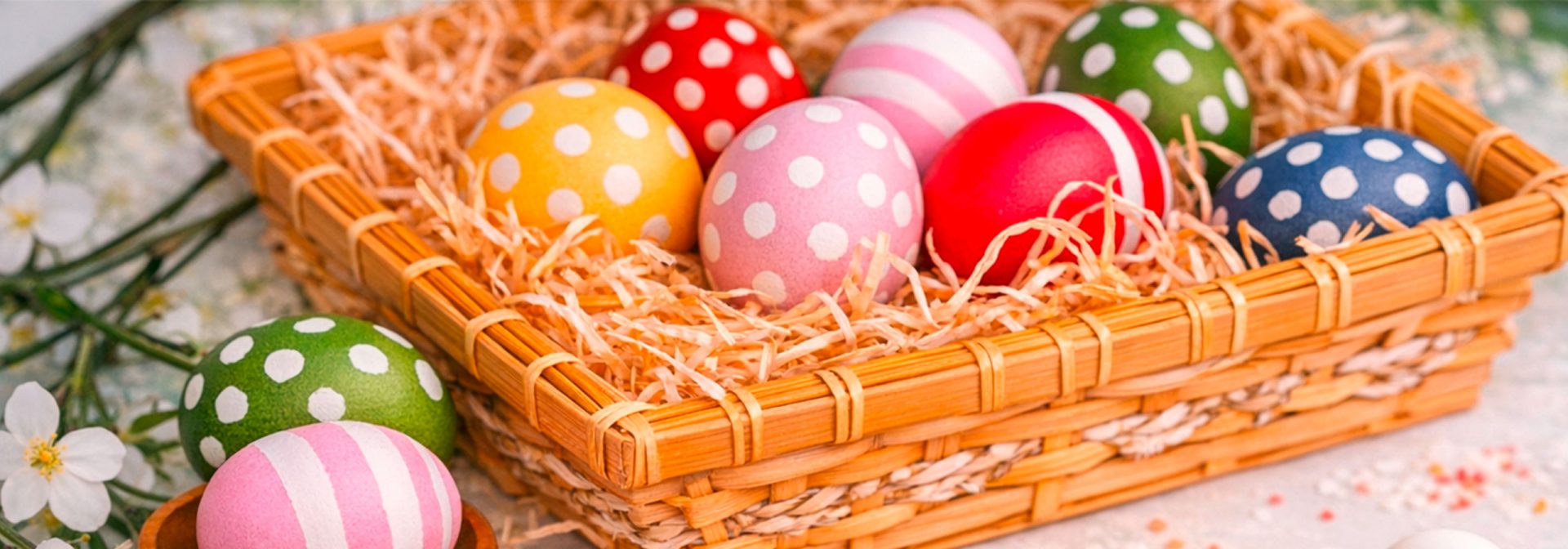 Bunte Ostereier mit Punkten und Streifen in einem Holz Korb mit Stroh.