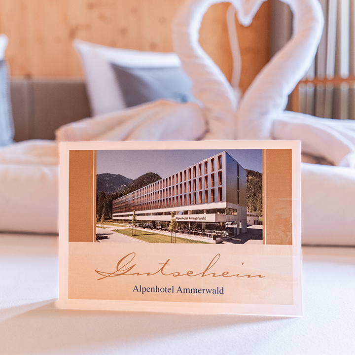 Bild eines Beispiel Gutscheines für das Alpenhotel Ammerwald, auf dem ein Bild vom Hotel abgebildet ist.