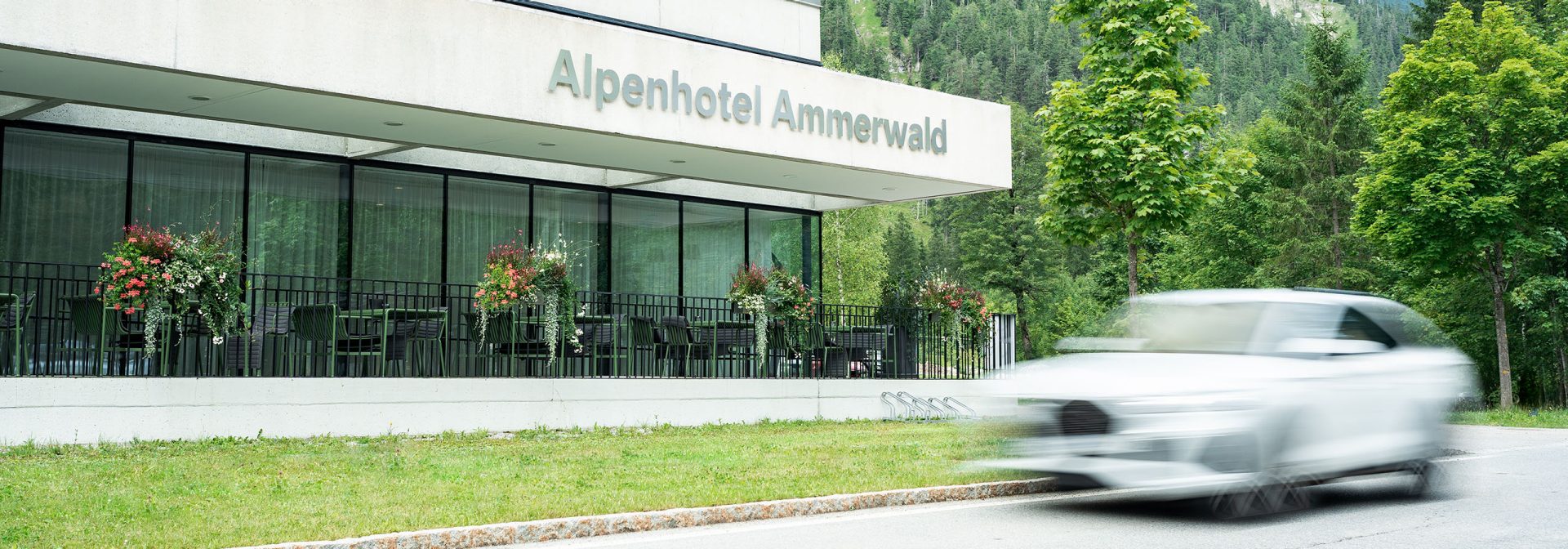 Exterior view of Alpenhotel Ammerwald with a white car passing by.