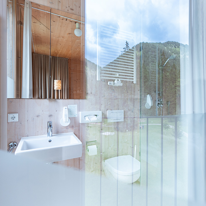 A sleek modern bathroom featuring a glass shower, wooden accents, and a white sink.