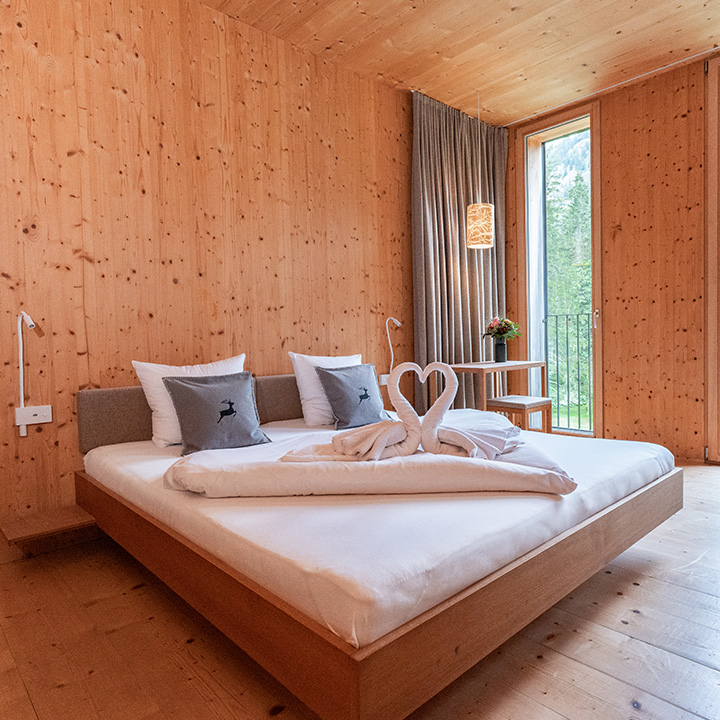 A cozy wooden bedroom featuring a heart-shaped towel arrangement on a neatly made bed.