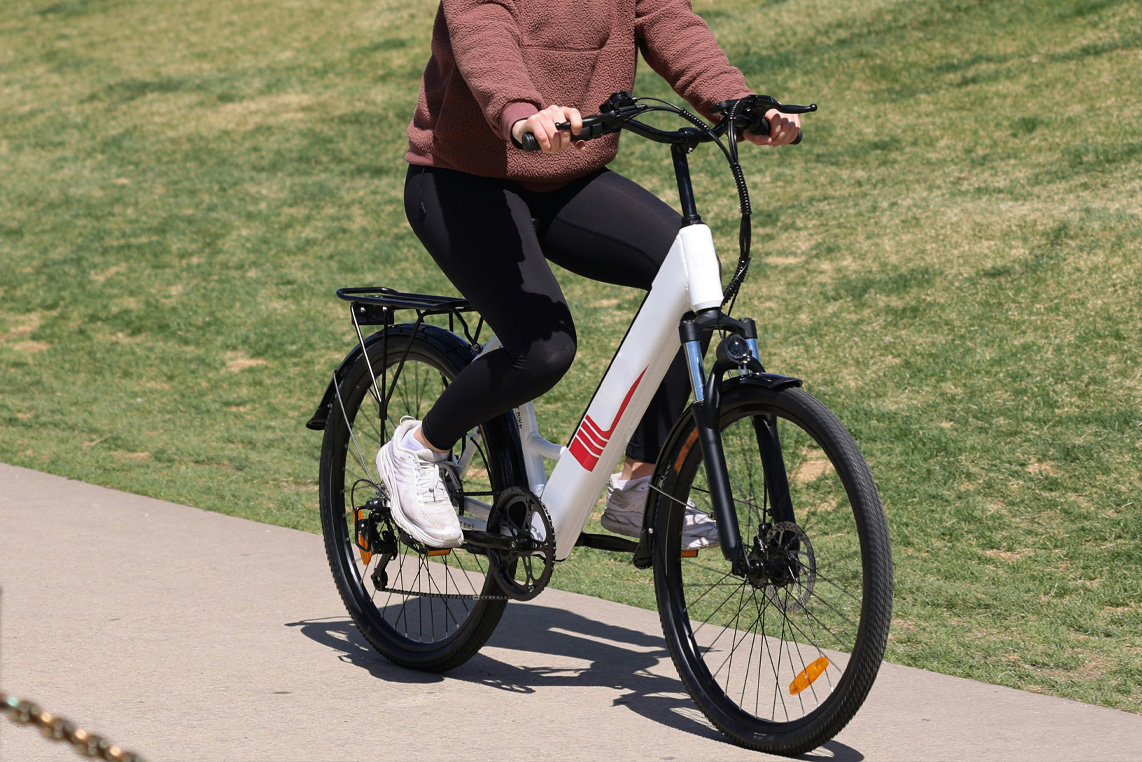 Eine Frau fährt auf einem E-bike einen Weg entlang.