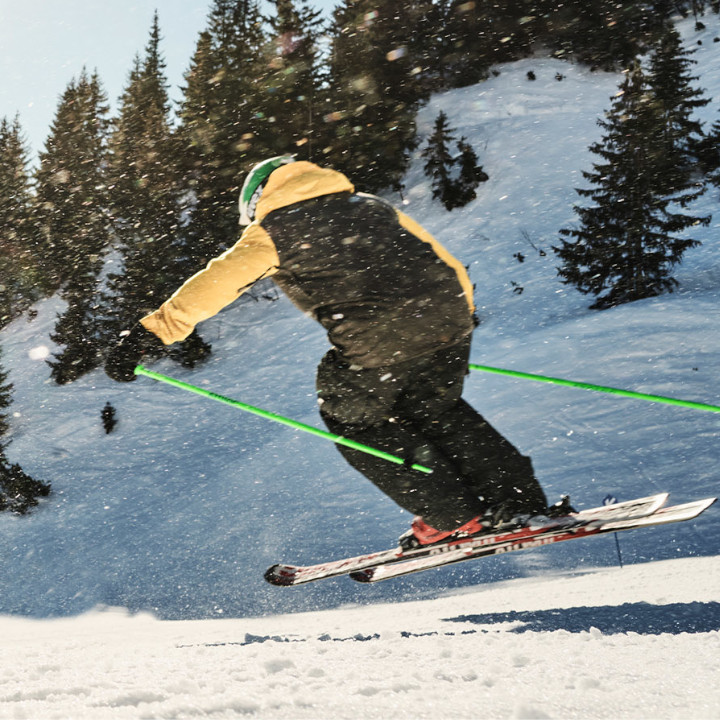 A skier performing a jump on a snowy mountain slope.