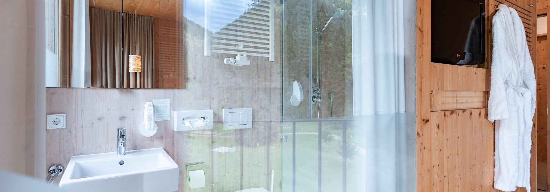A sleek modern bathroom featuring a glass shower, wooden accents, and a white sink.