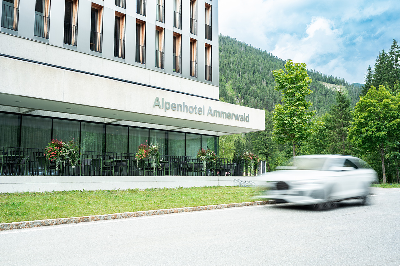 Exterior view of Alpenhotel Ammerwald with a white car passing by.