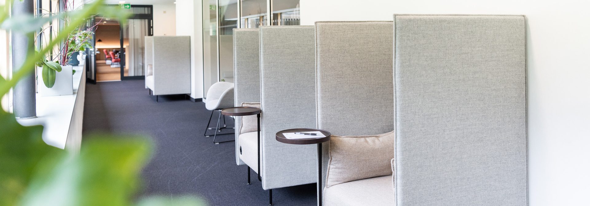 A stylish modern office seating area with gray upholstered chairs and small side tables.