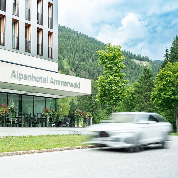 Exterior view of Alpenhotel Ammerwald with a white car passing by.