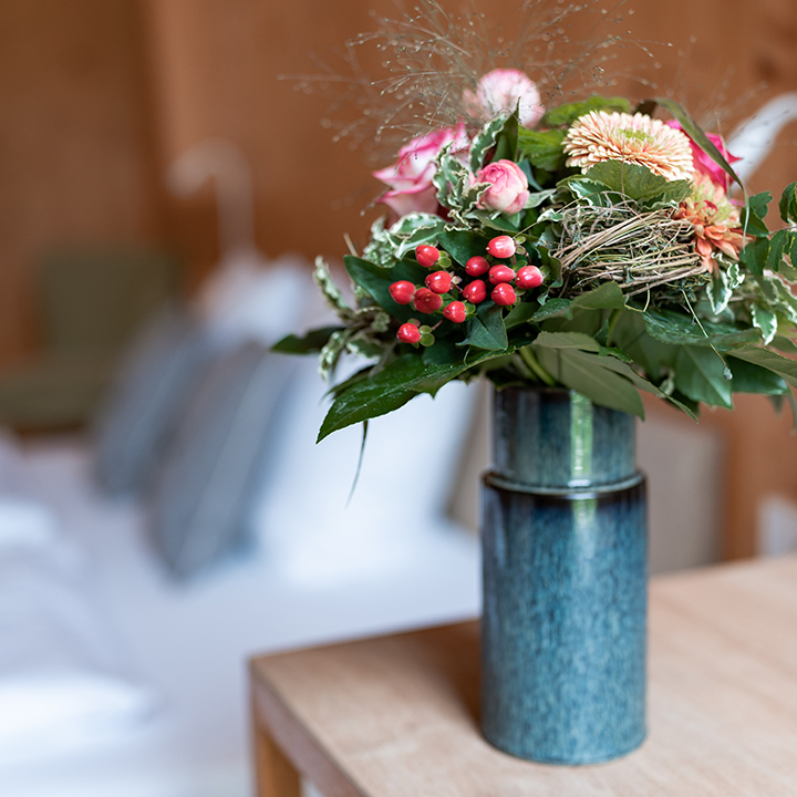 A vibrant flower arrangement featuring pink roses and greenery in a blue vase.