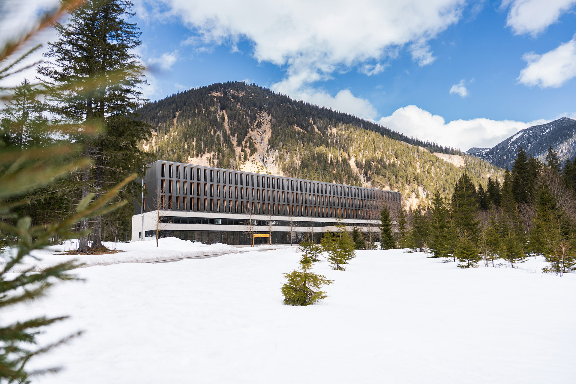 Exterior view of the Alpenhotel Ammerwald surrounded by snow and the mountains in the background