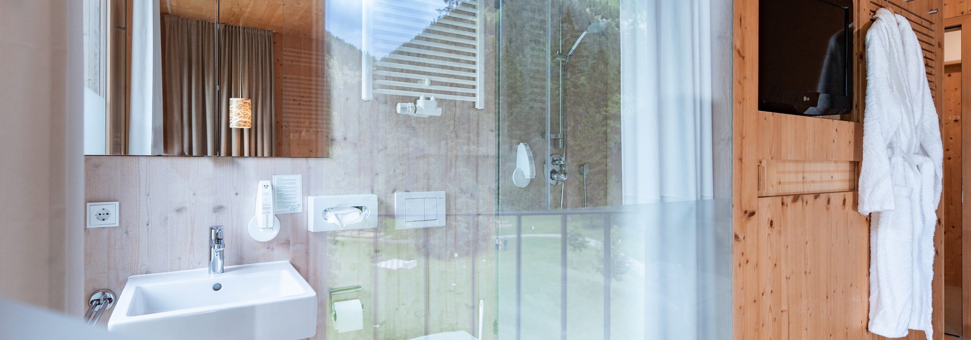 A sleek modern bathroom featuring a glass shower, wooden accents, and a white sink.