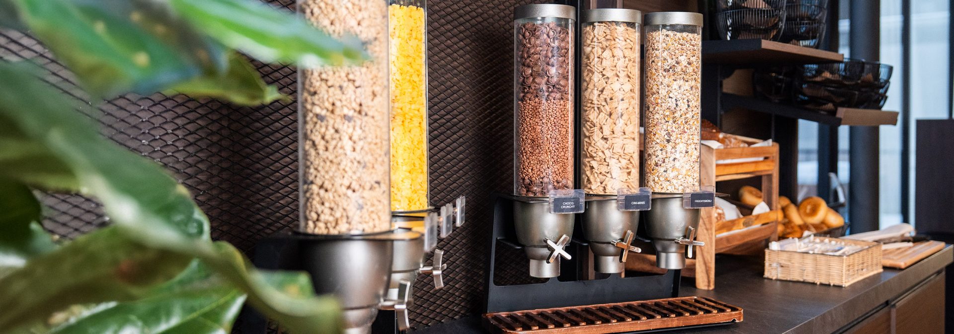 A modern cereal dispensing station with various cereals in clear containers.