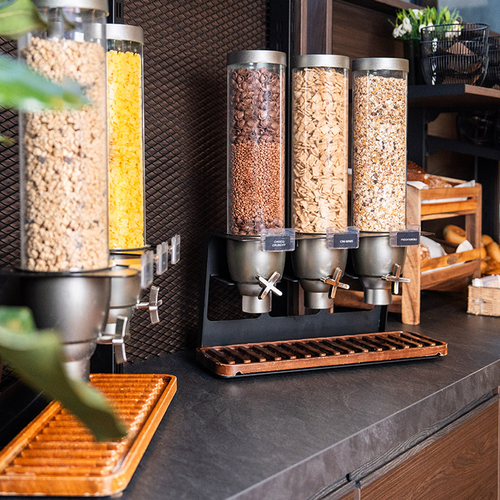 A modern cereal dispensing station with various cereals in clear containers.