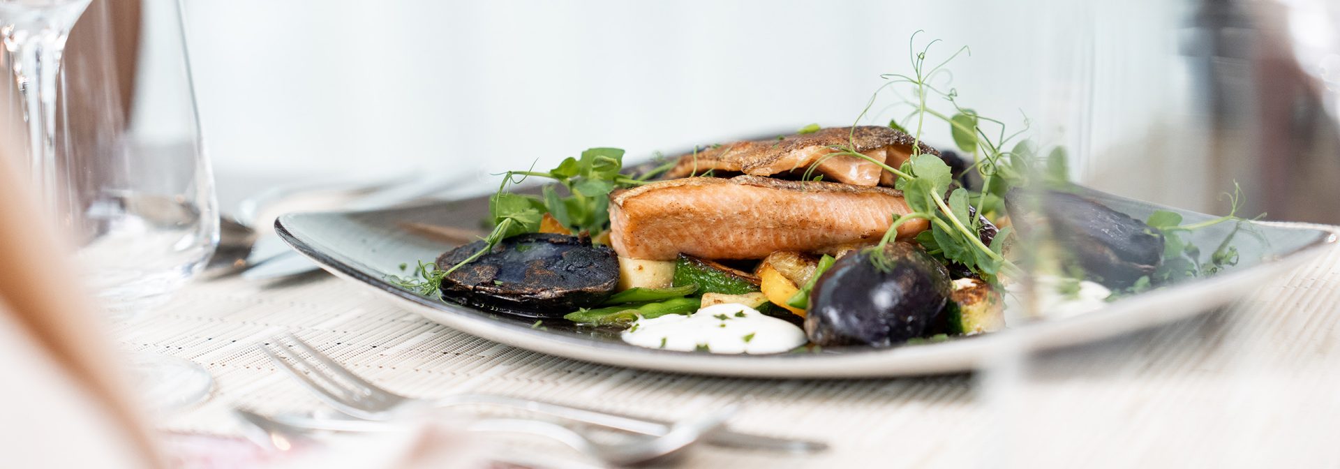 A beautifully plated dish featuring grilled fish, seasonal vegetables, and a creamy sauce.