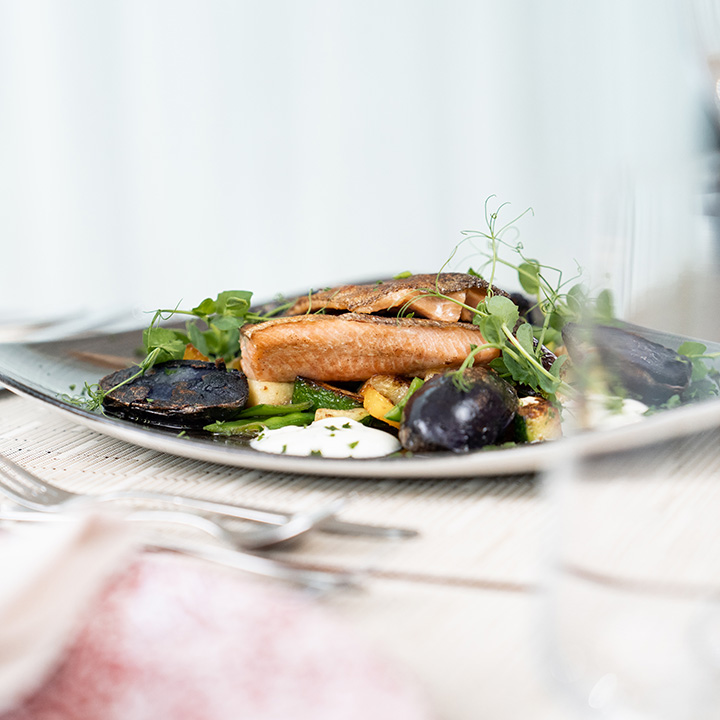 A beautifully plated dish featuring grilled fish, seasonal vegetables, and a creamy sauce.