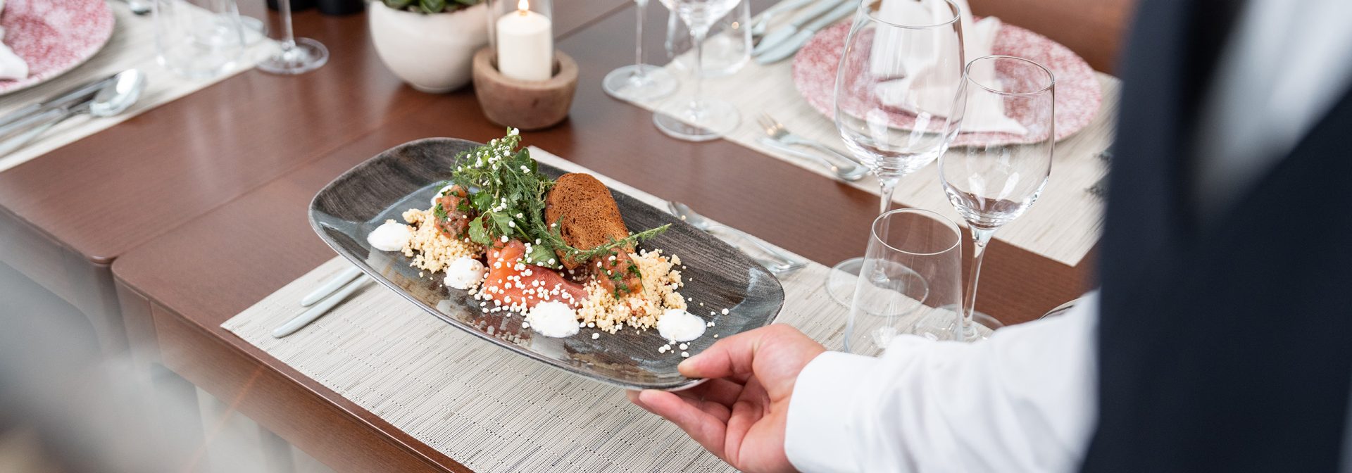 A beautifully plated gourmet dish with couscous, greens, and sauce.