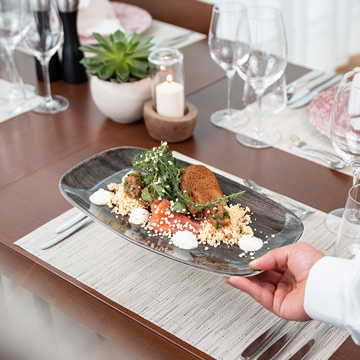 A beautifully plated gourmet dish with couscous, greens, and sauce.