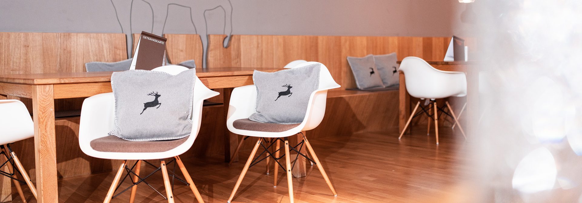 A stylish modern cafe interior featuring wooden tables and elegant chairs with deer-patterned cushions.