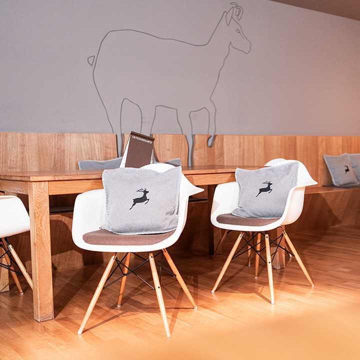 A stylish modern cafe interior featuring wooden tables and elegant chairs with deer-patterned cushions.