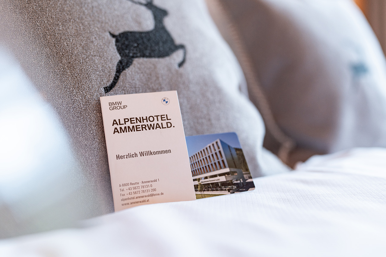 Key card for Alpenhotel Ammerwald with welcome message placed on a bed