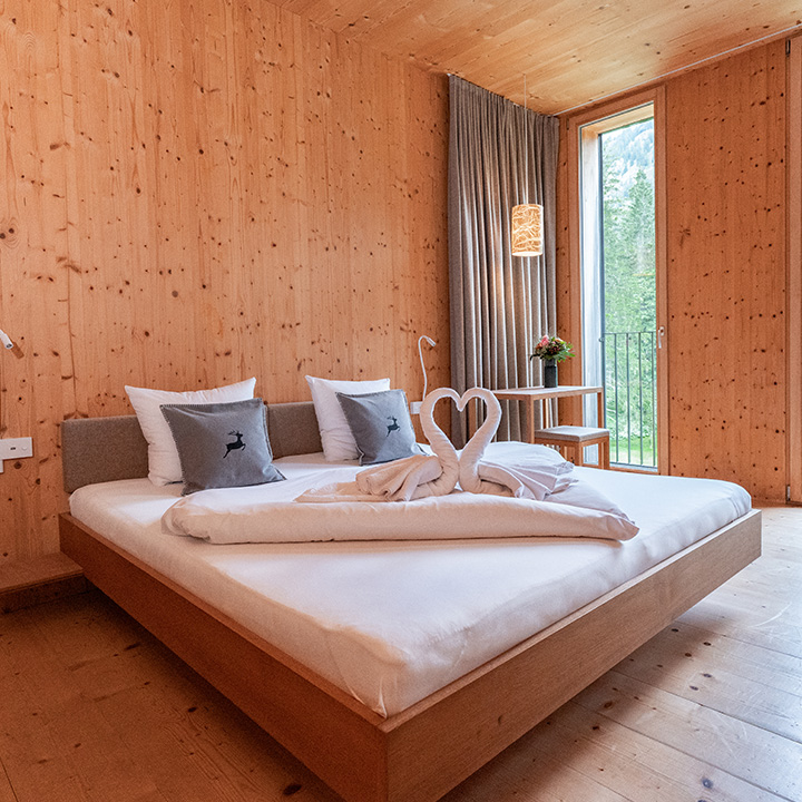 A cozy wooden bedroom featuring a heart-shaped towel arrangement on a neatly made bed.