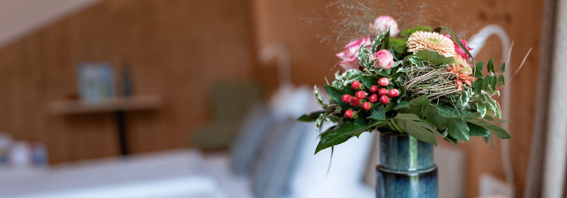 A vibrant flower arrangement featuring pink roses and greenery in a blue vase.