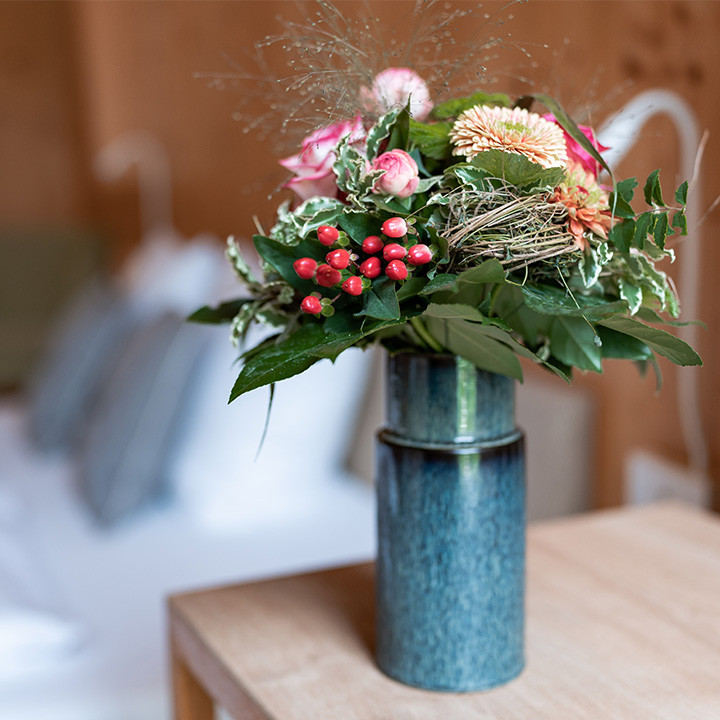 A vibrant flower arrangement featuring pink roses and greenery in a blue vase.