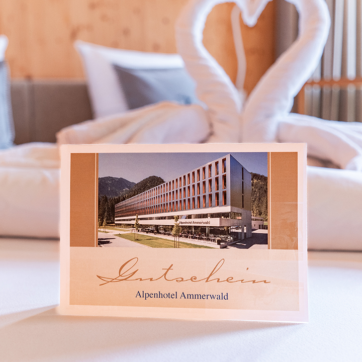 Voucher for Alpenhotel Ammerwald displayed on a bed