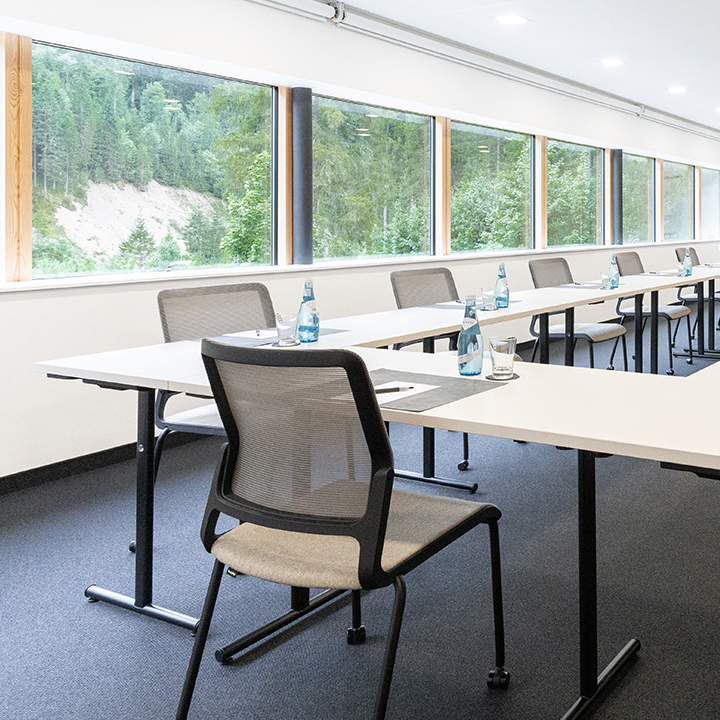 A modern conference room with tables and chairs set for a meeting.