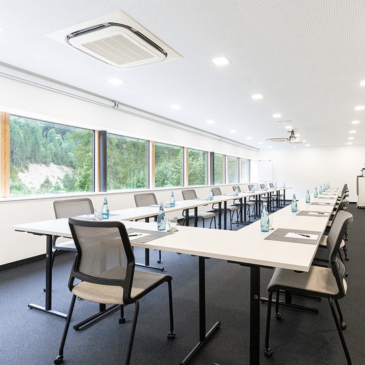 A modern conference room with tables and chairs set for a meeting.