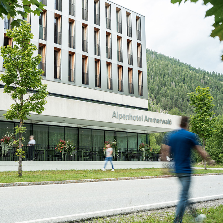 A man is walking past the Alpenhotel Ammerwald